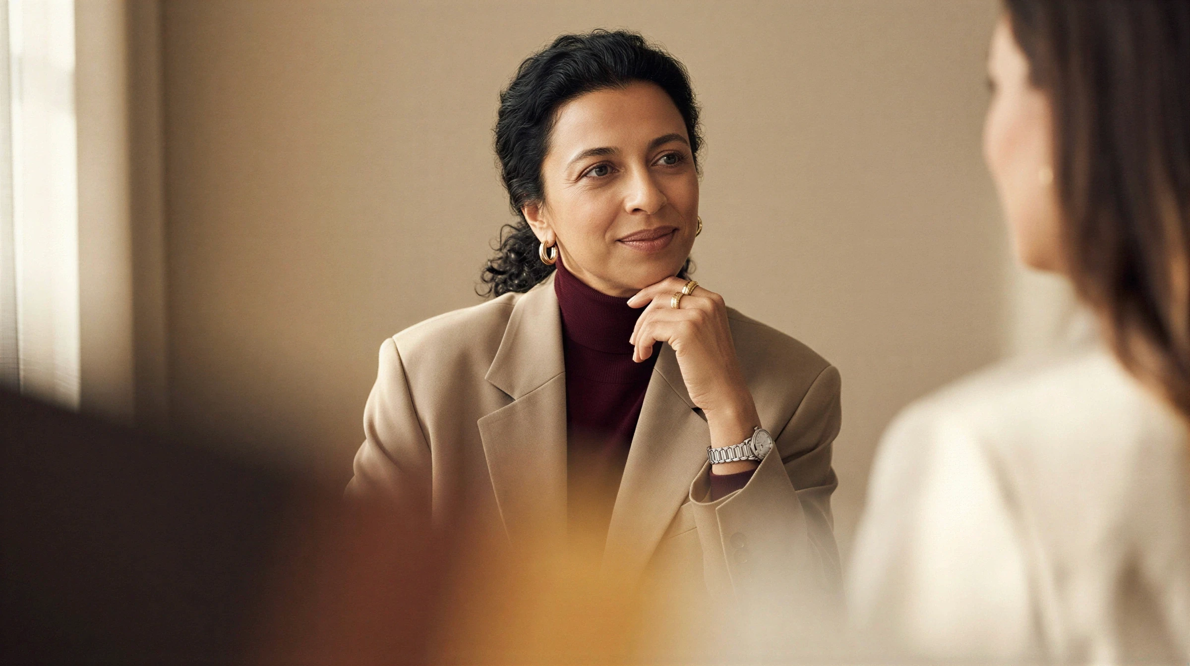 Femme en veston beige écoutant attentivement pendant une rencontre-conseil