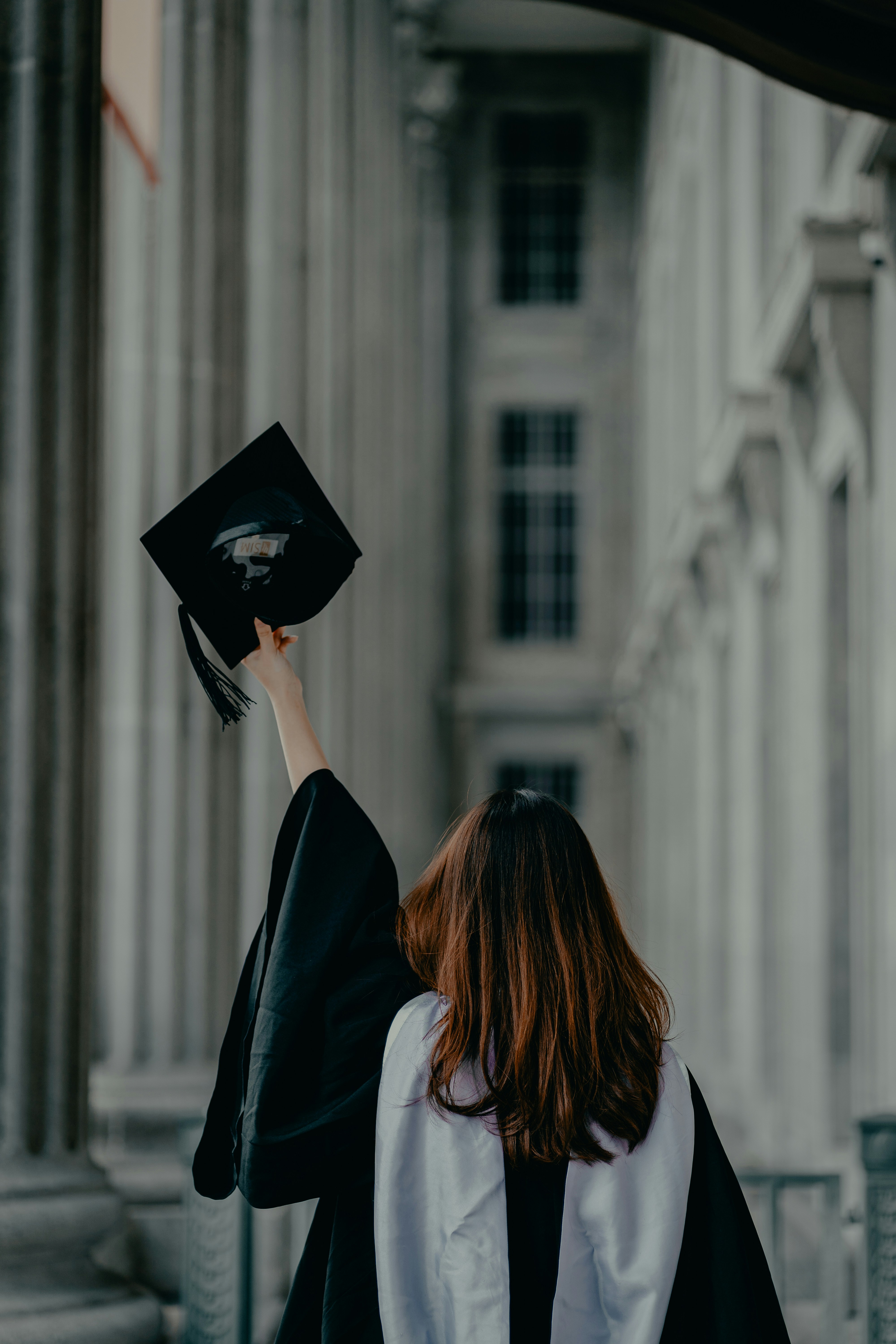 Diplômée levant son mortier devant un pavillon universitaire, illustration de l’épargne études REEE